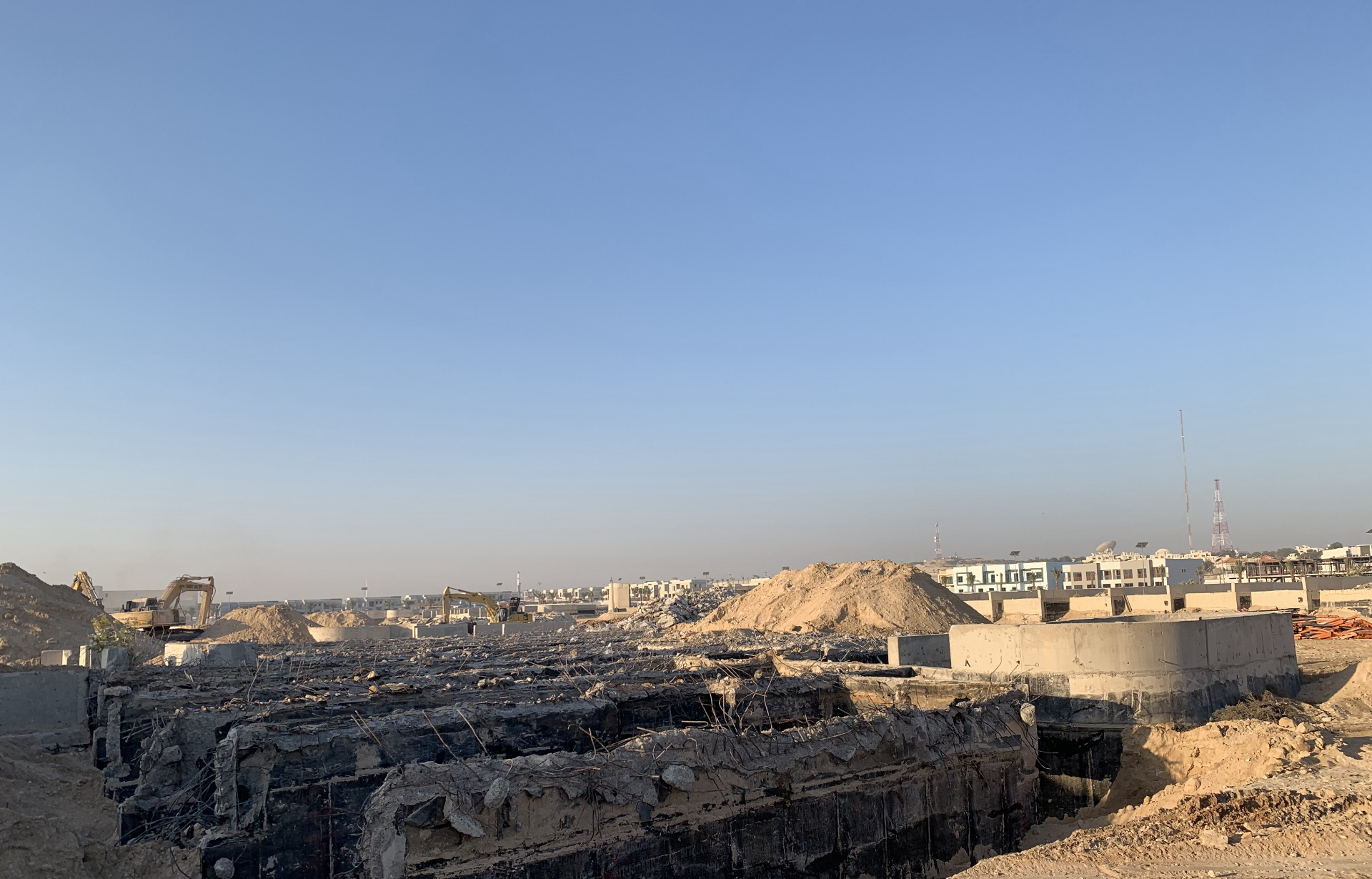 Excavators clearing demolished foundation with exposed rebar
