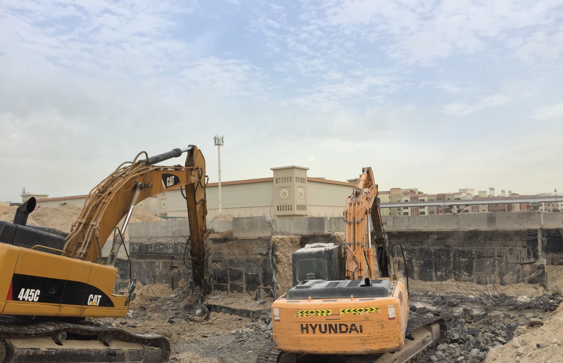 CAT and Hyundai excavators breaking concrete foundations