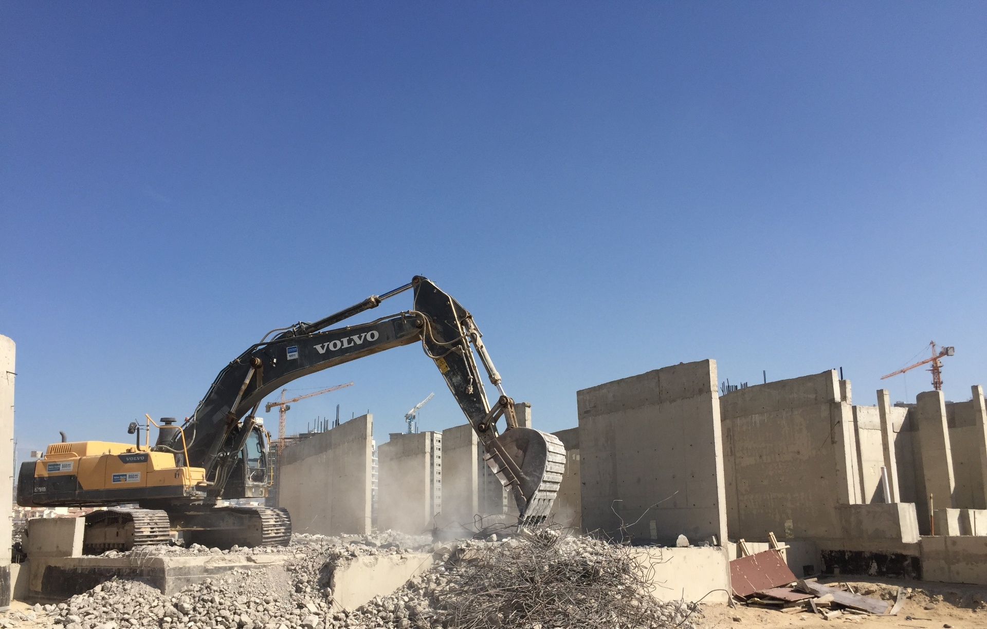 Volvo excavators clearing foundation debris against blue sky