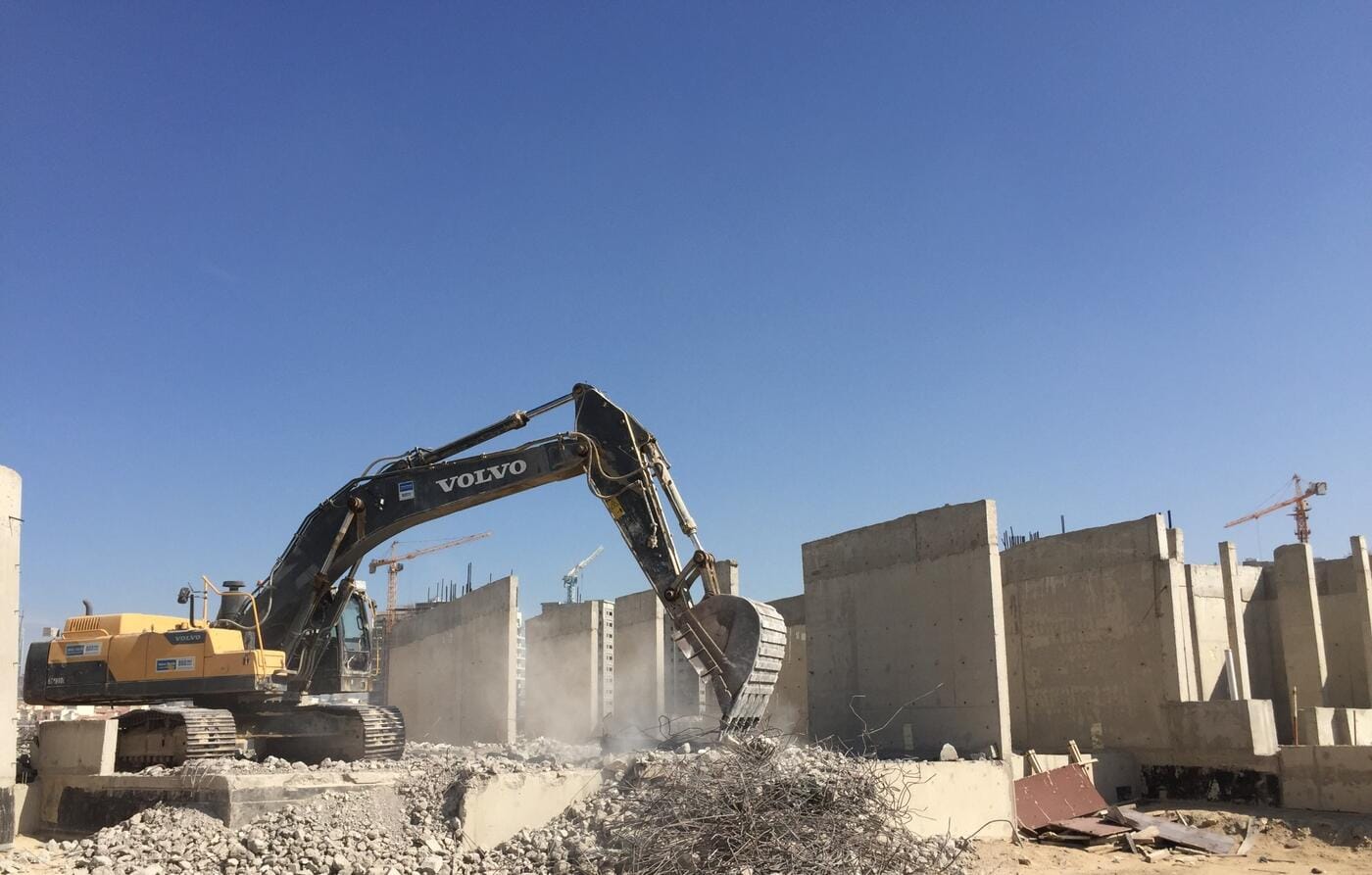 Volvo excavators clearing foundation debris against blue sky