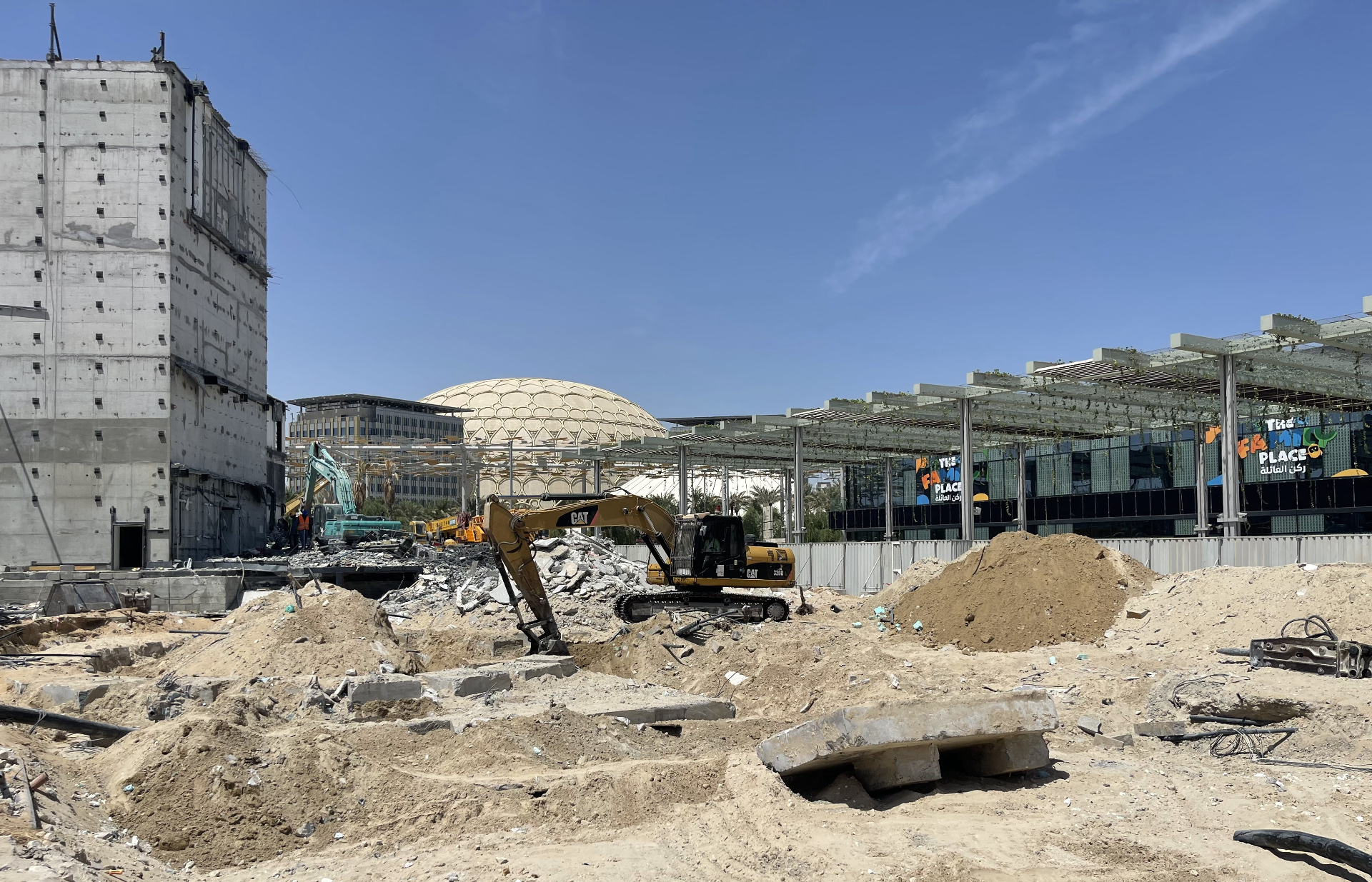 CAT excavators clearing ICD Pavilion demolition site with Al Wasl dome