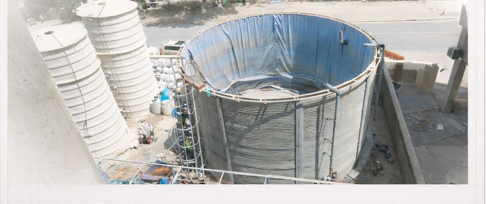 Wide view of sewerage treatment storage tanks and lined process pit at Jebel Ali camp before demolition