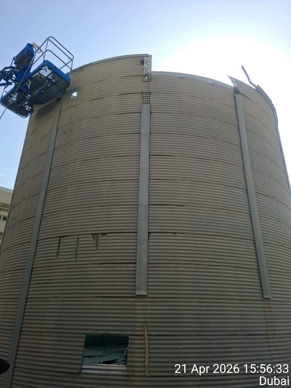Cherry picker positioned beside corrugated steel tank during controlled demolition at G+2 G+3 camp Jebel Ali Dubai