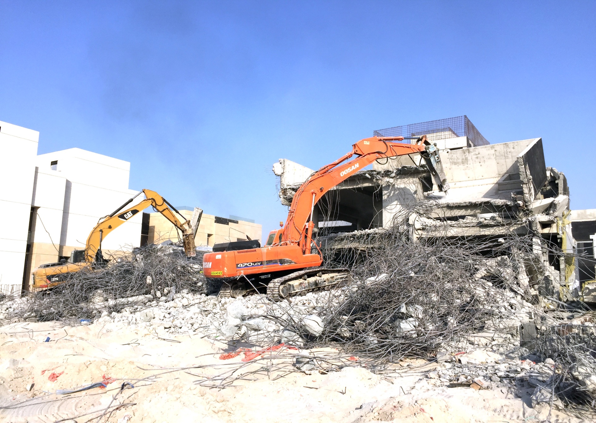 Multiple excavators at villa demolition site with Doosan equipment