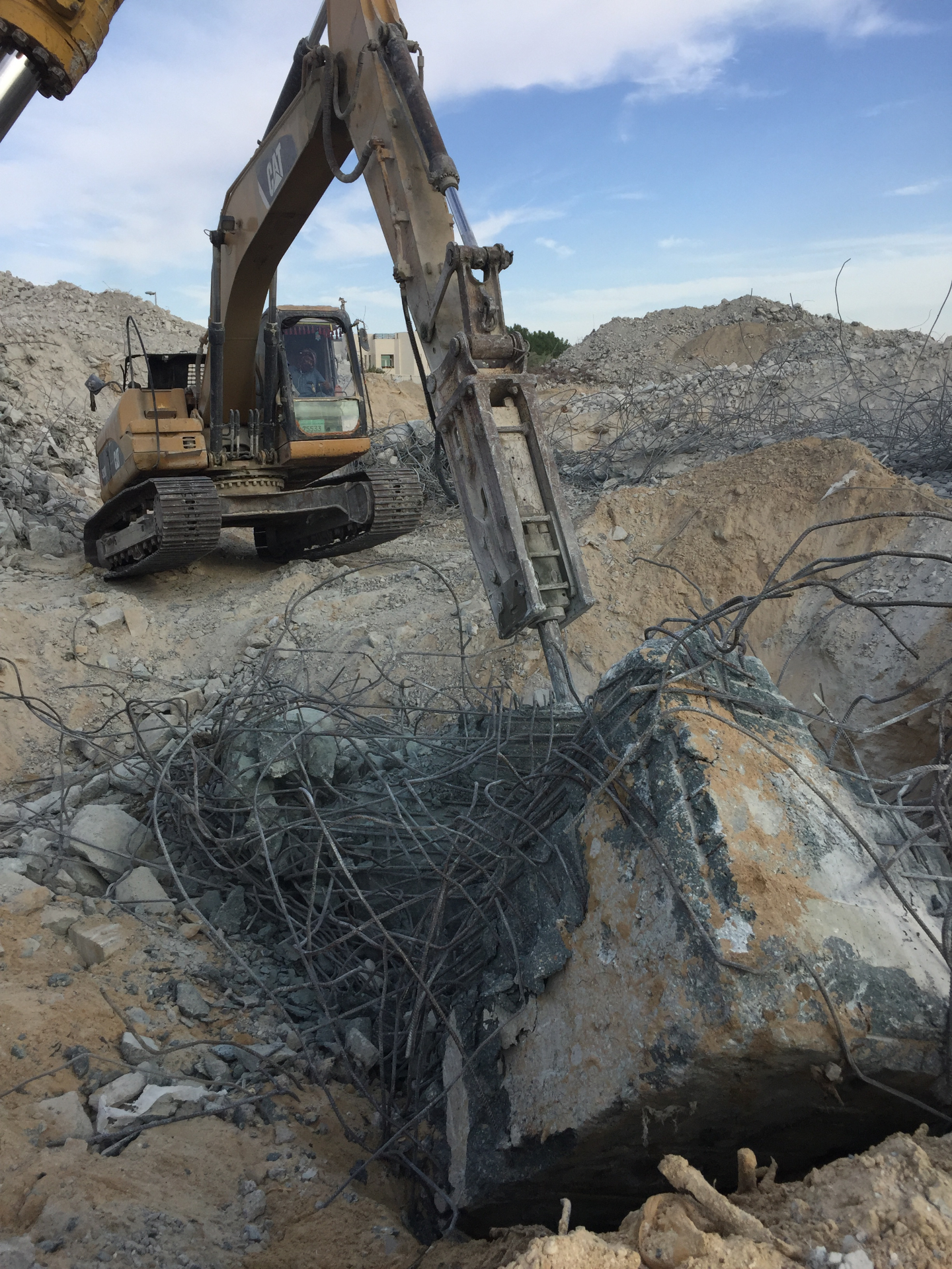 CAT excavator removing foundation with reinforced steel