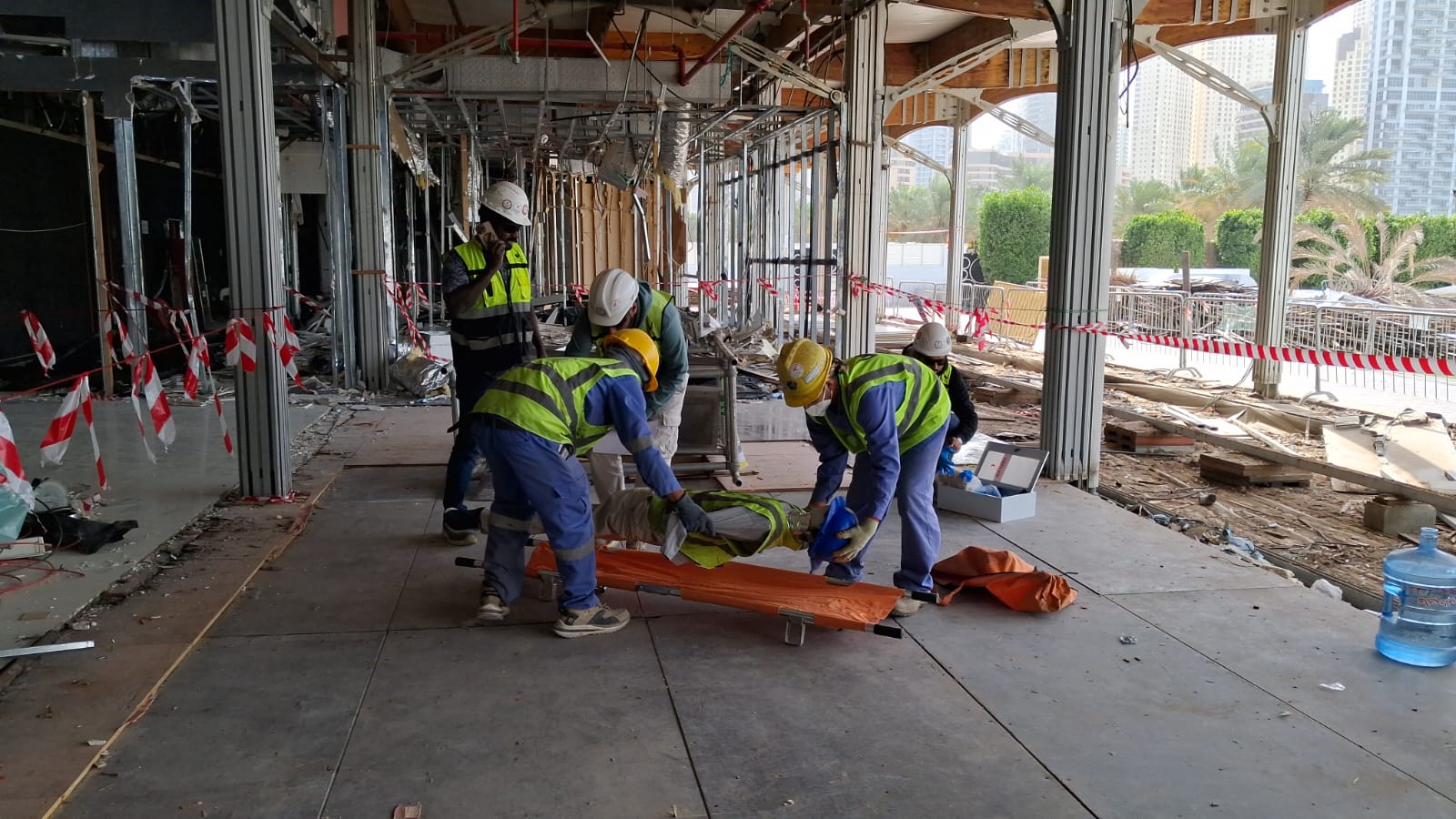 Workers placing simulated casualty on stretcher during emergency drill at Marina Harbor