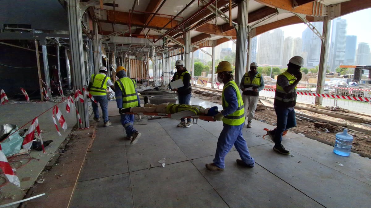 Emergency mock drill inside demolition site with safety personnel and stretcher