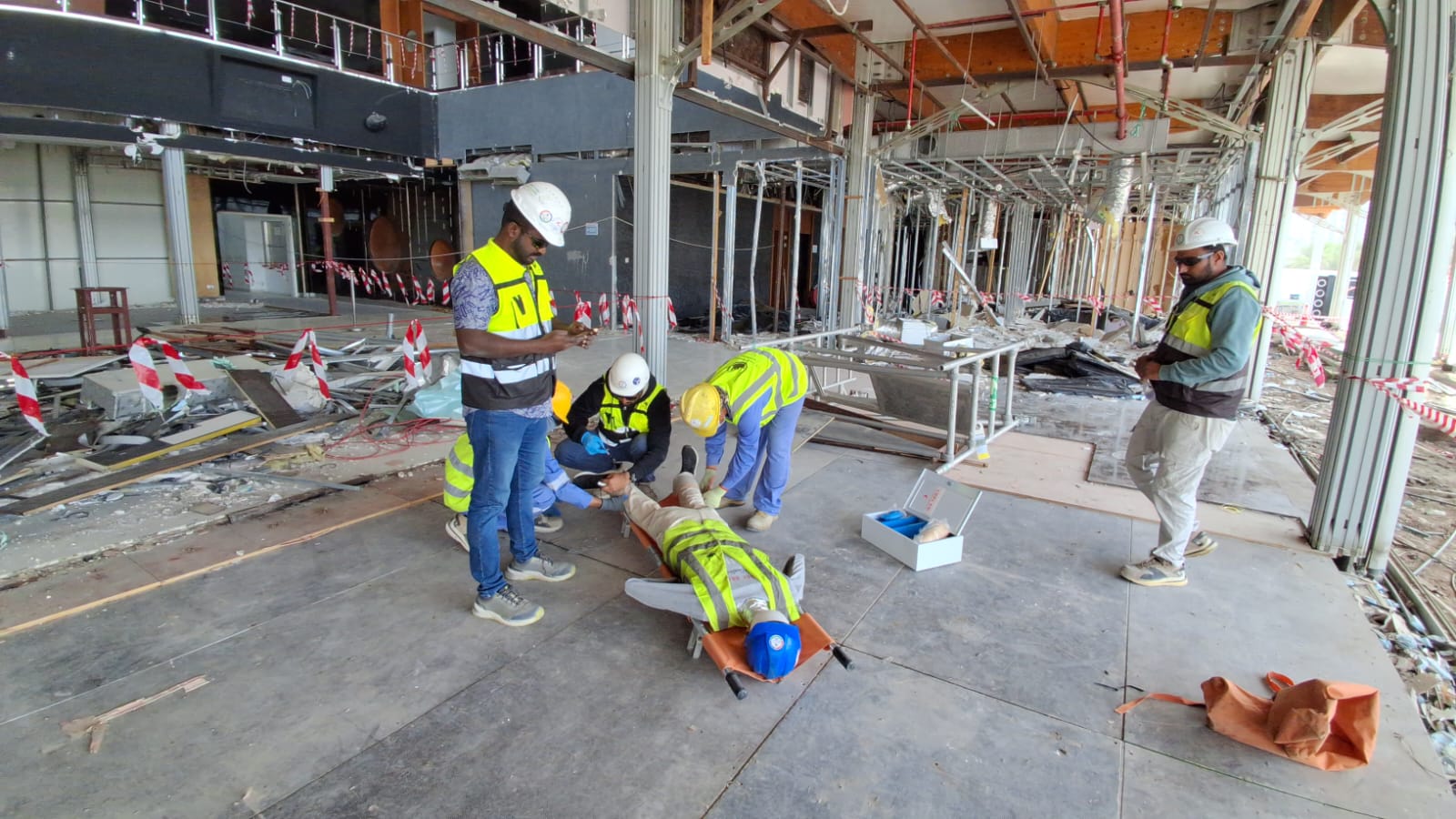 Emergency responders providing care to simulated injured worker at demolition site