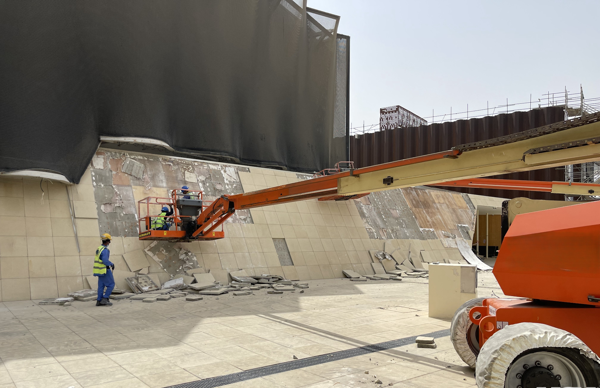 Boom lift workers removing facade cladding from New Zealand Pavilion