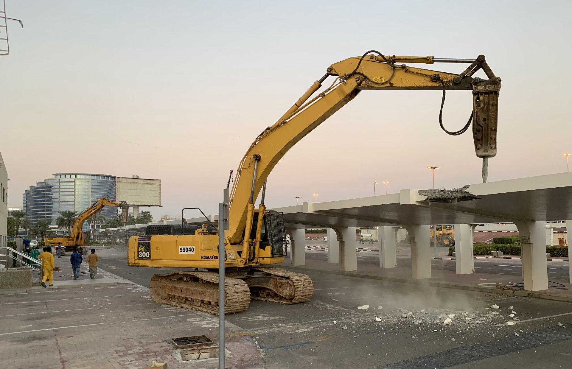 Komatsu excavator with breaker attachment demolishing concrete shade