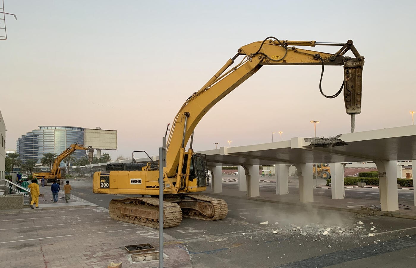 Komatsu excavator with breaker attachment demolishing concrete shade