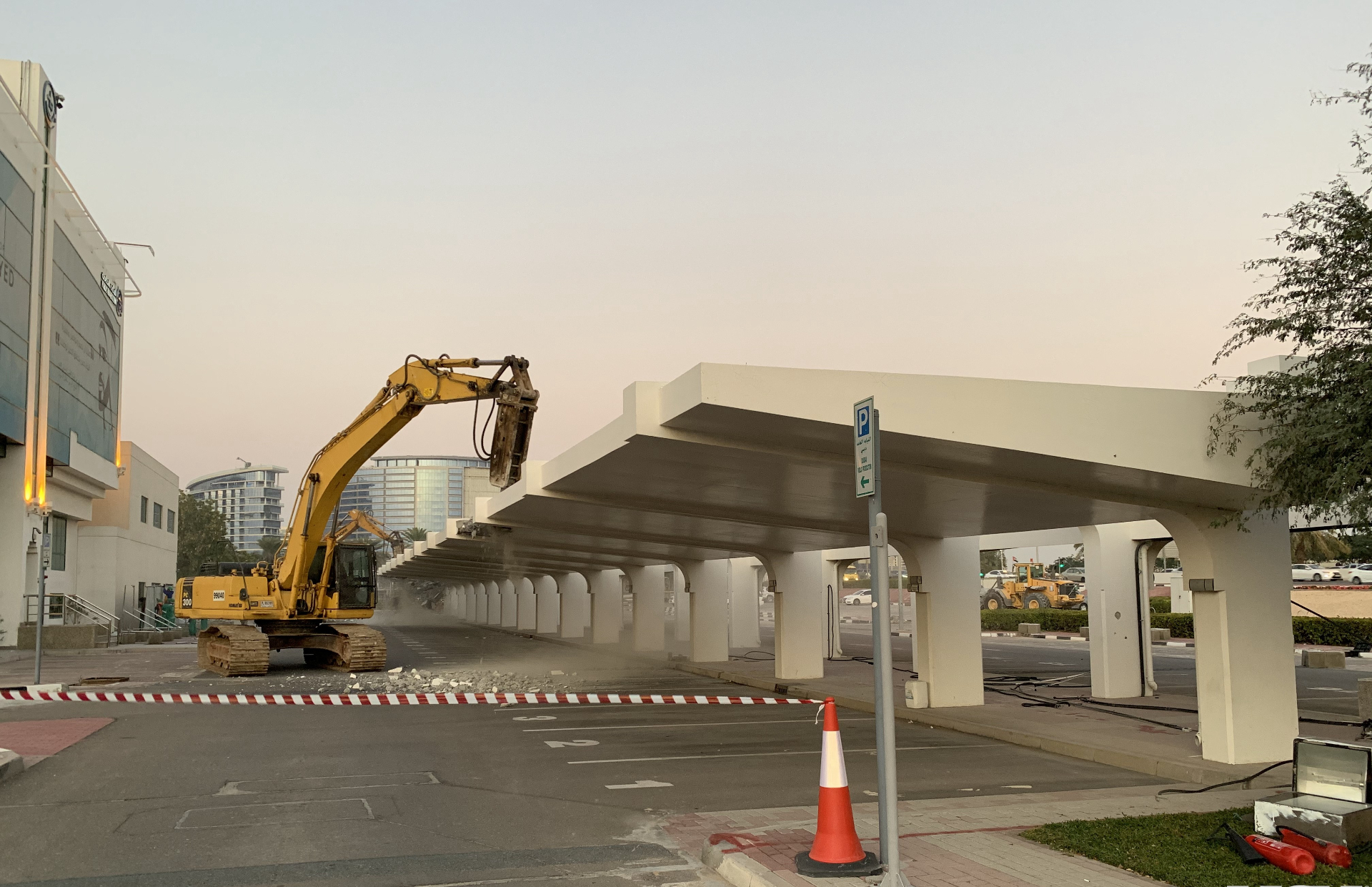 Excavator demolishing parking structure with safety barriers