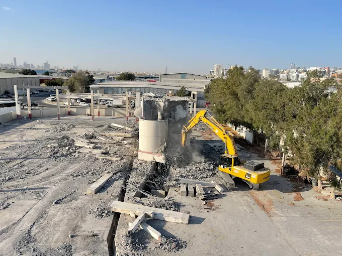 USF excavator dismantling reinforced concrete structure during active site clearance