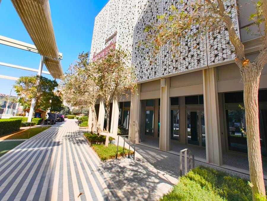 Women's Pavilion entrance walkway with trees and facade cladding