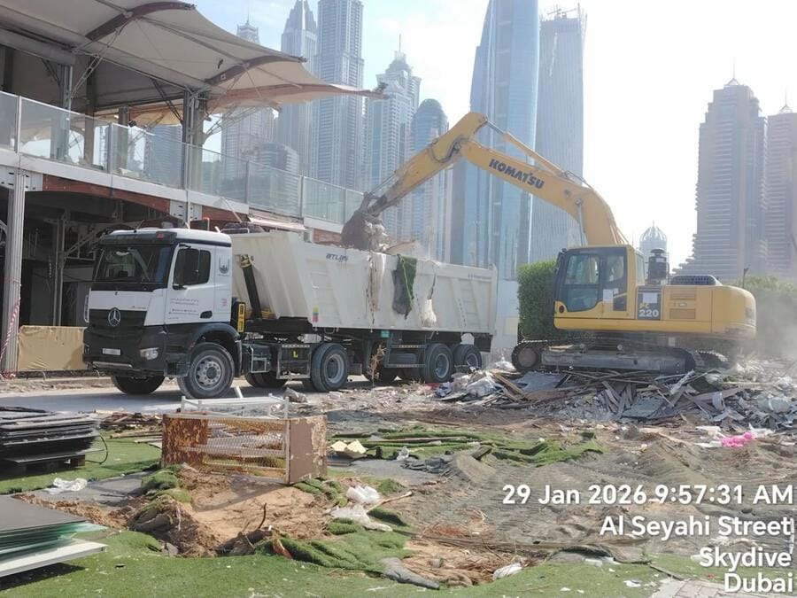 Komatsu excavator loading debris with Dubai Marina skyline at Zero Gravity demolition site