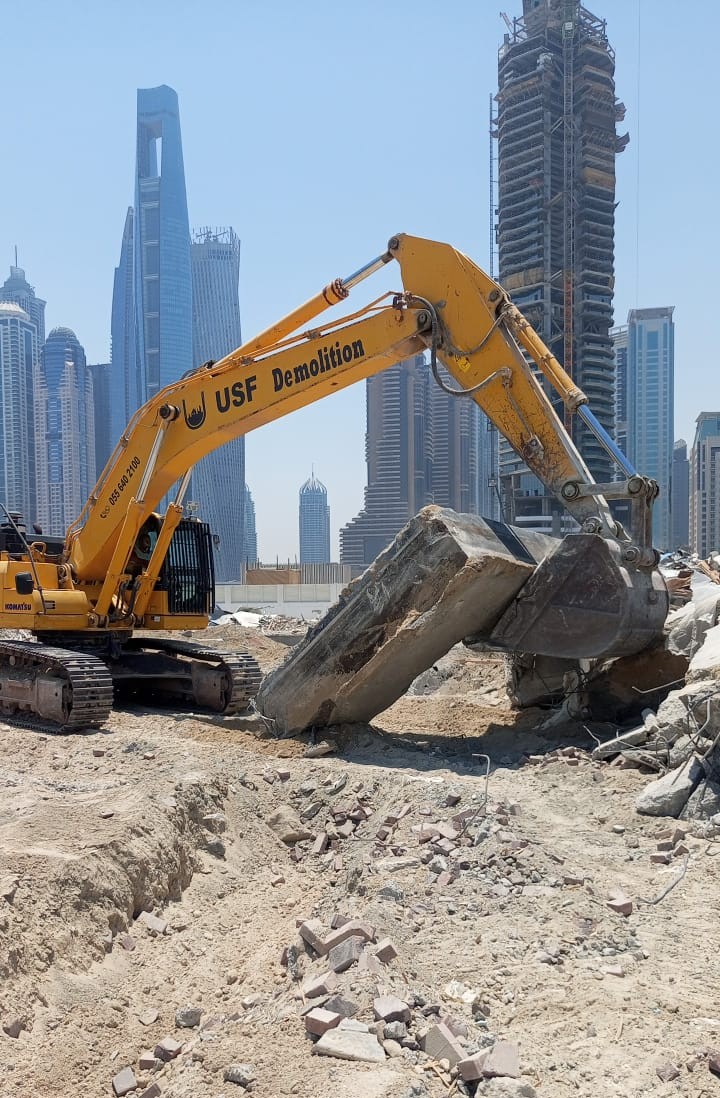 USF Demolition Komatsu PC400 excavator processing concrete debris with Dubai Marina skyline at Zero Gravity site clearance