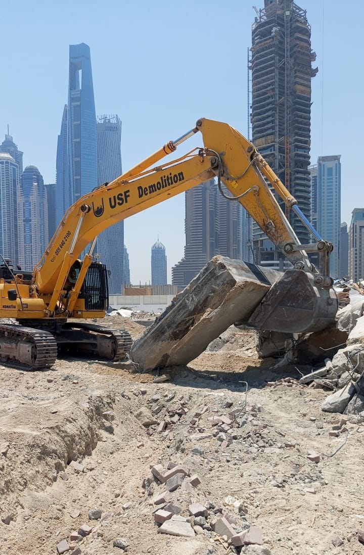 USF Demolition Komatsu PC400 excavator processing concrete debris with Dubai Marina skyline at Zero Gravity site clearance