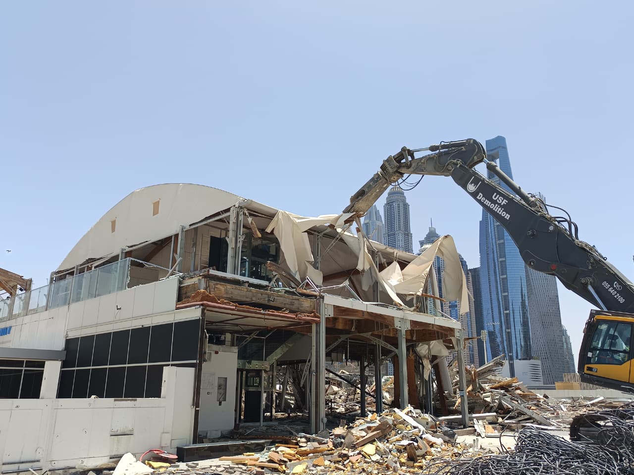 USF Demolition long-reach excavator dismantling Zero Gravity tensile canopy upper structure with Dubai Marina skyline